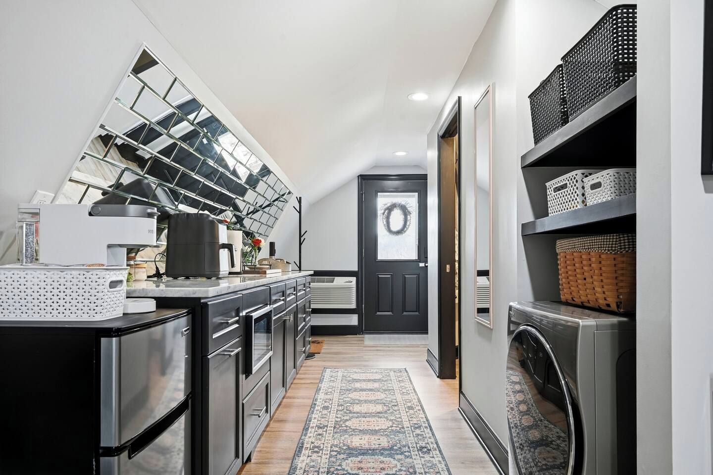 Una cucina moderna con una grande finestra, elettrodomestici integrati e una porta nera decorata con un festone.