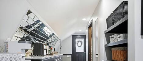 A modern kitchen with a large window, built-in appliances, and a black door with a wreath.
