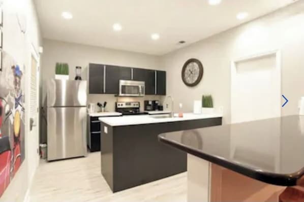 A modern kitchen with black cabinets, stainless steel appliances, and a central island.