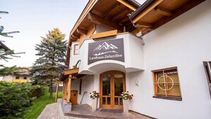 Un edificio con un cartello che riporta 'Landhaus-ZellamSee', un ingresso in legno e un vialetto lastricato che conduce alla porta.