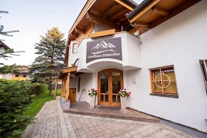 Ein Gebäude mit einem Schild, das 'Landhaus-ZellamSee' zeigt, einem hölzernen Eingang und einem gepflasterten Weg zum Eingangsbereich.