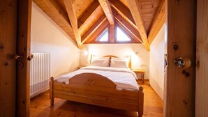 Camera mansardata con struttura in legno, caratterizzata da un tetto spiovente, un letto, un comodino e un termosifone.