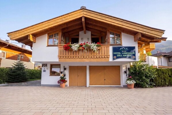 Un hotel con fachada de madera, balcones con jardineras florales y un letrero que indica que es un hotel de montaña.