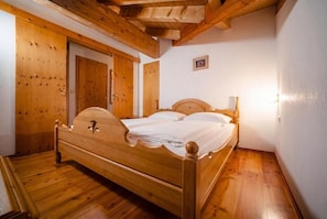 A wooden four-poster bed in a room with wooden floors and walls, a wooden door, and a small framed picture on the wall. - Landhaus Zell am See (Zell am See)