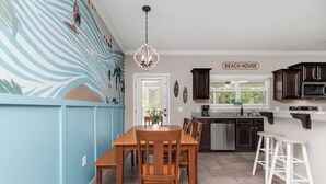Een keuken met een eethoek, een kroonluchter en een bord met de tekst 'BEACH HOUSE'.