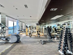 Ein Fitnessstudio mit Cardiogeräten, Kurzhanteln und einer Spiegelwand.