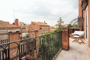 A balcony with a metal railing, a white chair, and a view of neighboring buildings. - Historic Dorsoduro Apartment with Balcony Near Guggenheim & Zattere (Venezia)
