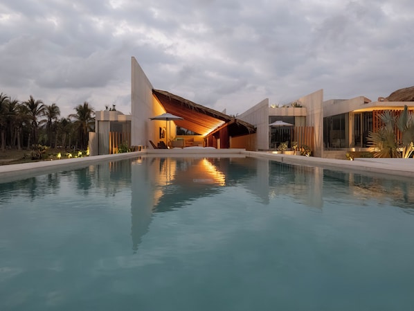 A modern resort with a pool, palm trees, and a building with a unique roof design. - Casa Talá by Lumina (Santa María Colotepec)