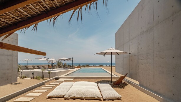 A beachside pool area with lounge chairs, umbrellas, and a view of the ocean. - Casa Talá by Lumina (Santa María Colotepec)
