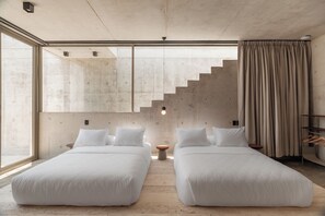 Ein modernes Hotelzimmer mit zwei Betten, einem großen Fenster, einer Treppe und einem Kleiderschrank.