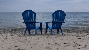 Two blue chairs facing the sea on a pebbly beach. - Lakefront cottage #1 with private beach on Lake Huron, AC, shared Hot Tub & Pool (Lexington)