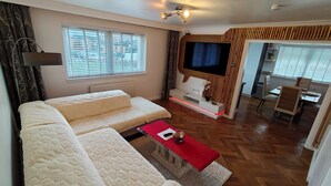 Un salon comprenant un canapé, un téléviseur, un coin repas et un mur décoratif en bois.