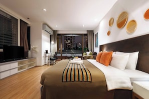 Ein modernes Hotelzimmer mit einem großen Bett, einem Fernseher, einem Schreibtisch und Blick auf die Stadt.