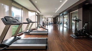 Un gimnasio con cintas de correr, bicicletas estáticas y máquinas de pesas.