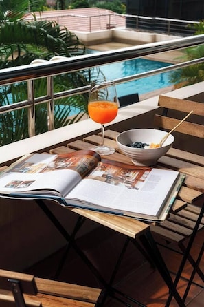 Ein Poolbereich mit Buch, Orangensaftglas und Obstschale auf einem Holztisch.