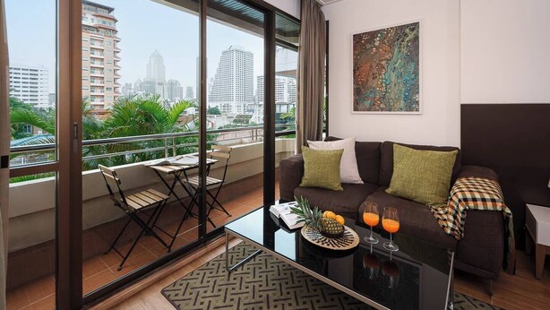 Un salón moderno con balcón, un conjunto de sofá, una mesa de centro y vistas a la ciudad.