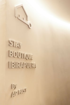 Uma parede com um recorte em formato de fechadura e o texto 'STAY BOUTIQUE IBIRAPUERA BY APFAST'.