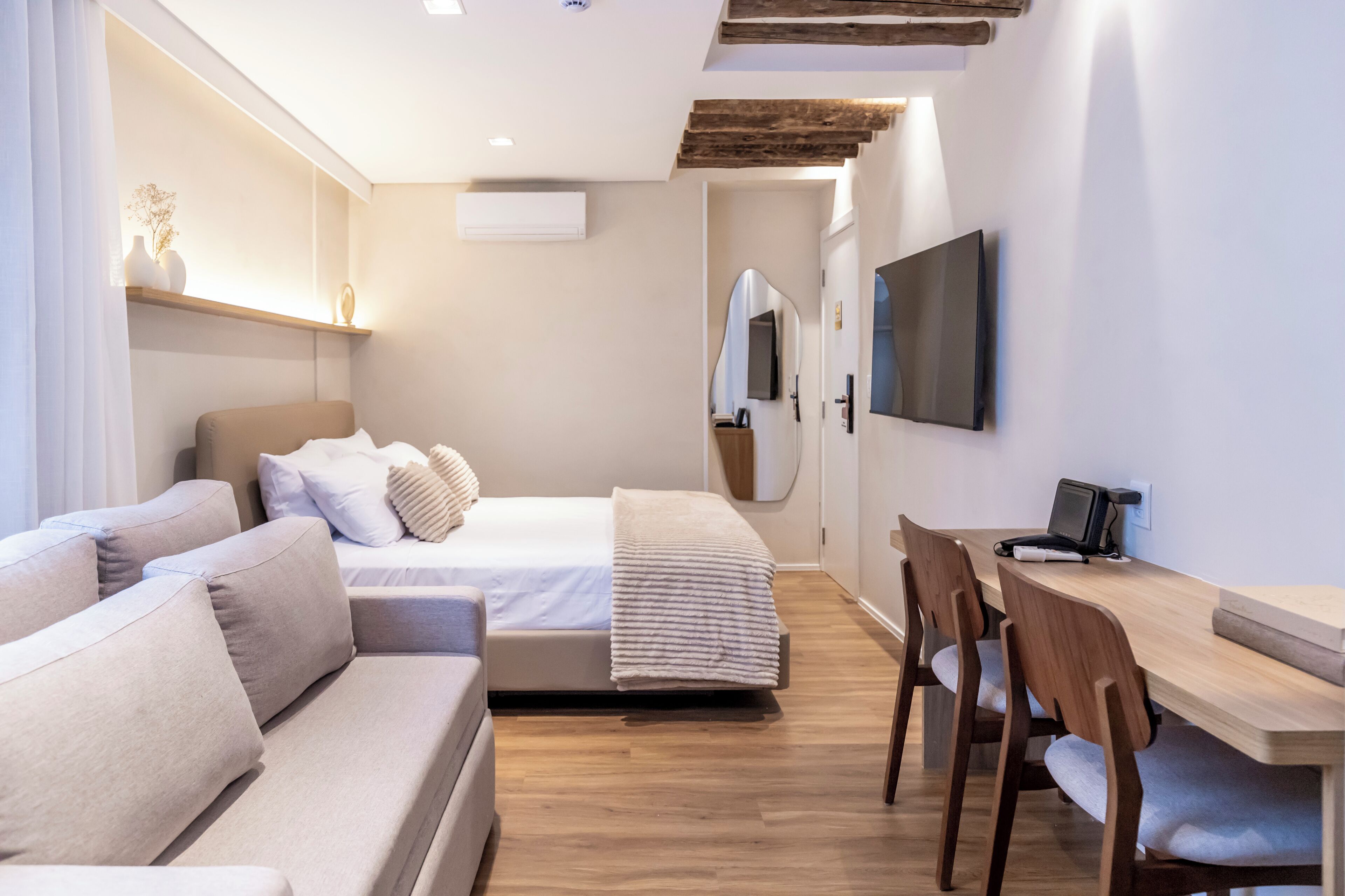 Una habitación de hotel moderna con sofá, cama, escritorio y televisor.