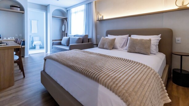 A modern hotel room with a large bed, a desk, and a view of the outdoors. - Stay Boutique Ibirapuera (São Paulo)