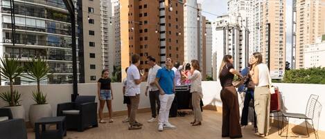 Una terraza en la azotea con mobiliario exterior y vistas a rascacielos.