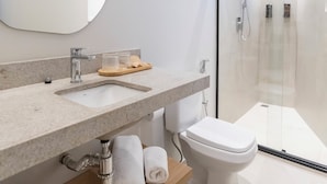 A modern bathroom with a large mirror, a sink, a toilet, and a glass-enclosed shower. - Stay Boutique Ibirapuera (São Paulo)