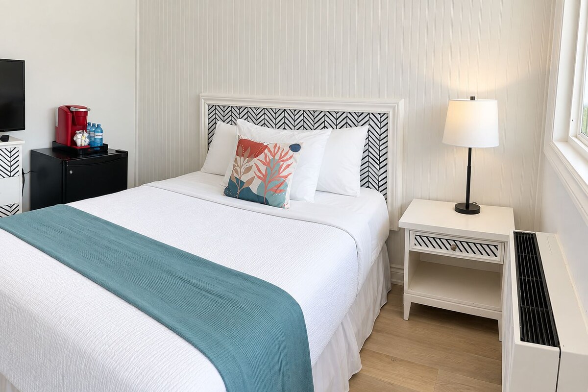 A neatly arranged hotel room with a bed, bedside tables, a lamp, and a television.