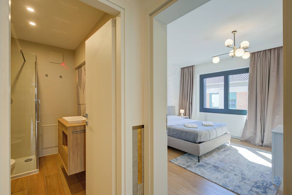 A modern bedroom with a bed, bedside table, and a window.
