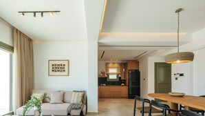 A modern living room with a sofa, coffee table, and dining area. - Vendema Residence Mykonos (Mikonos)