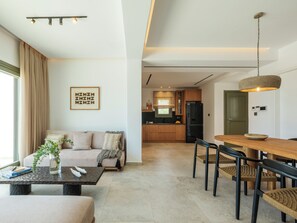 A modern living room with a sofa, coffee table, and dining area. - Vendema Residence Mykonos (Mikonos)