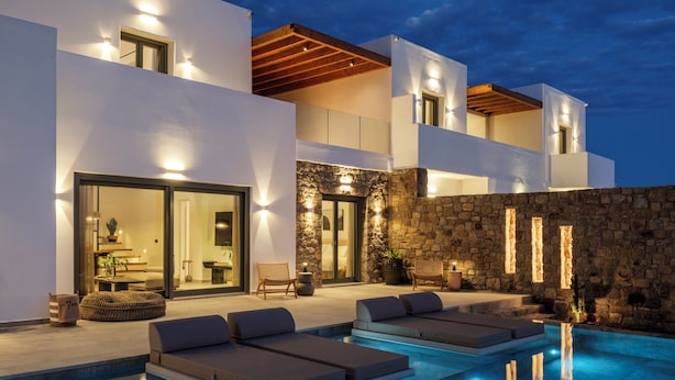 A modern pool area with built-in seating and a stone wall. - Vendema Residence Mykonos (Mikonos)