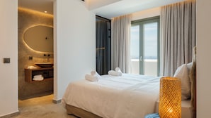 A modern hotel room with a large bed, a round mirror, a built-in sink, and a balcony with curtains. - Vendema Residence Mykonos (Mikonos)