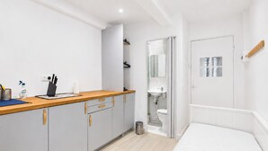 Quarto moderno e bem iluminado, com cozinha compacta, cama e banheiro.