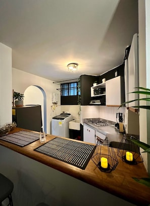 Une cuisine moderne dotée d’un plan de travail en bois, d’une cuisinière encastrée et d’un four à micro-ondes.