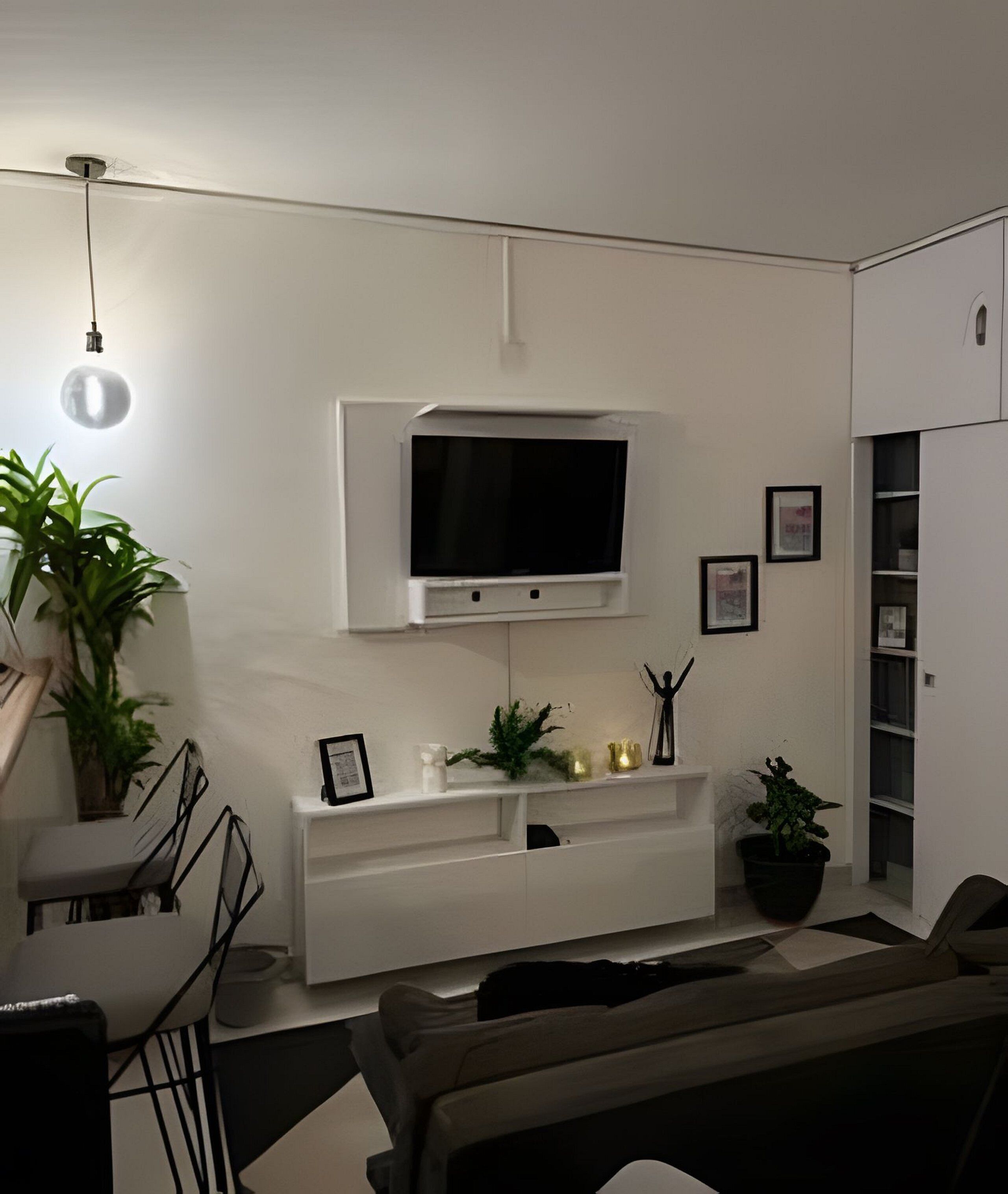 A living room with a mounted TV, white walls, a sofa, a dining table, and potted plants.