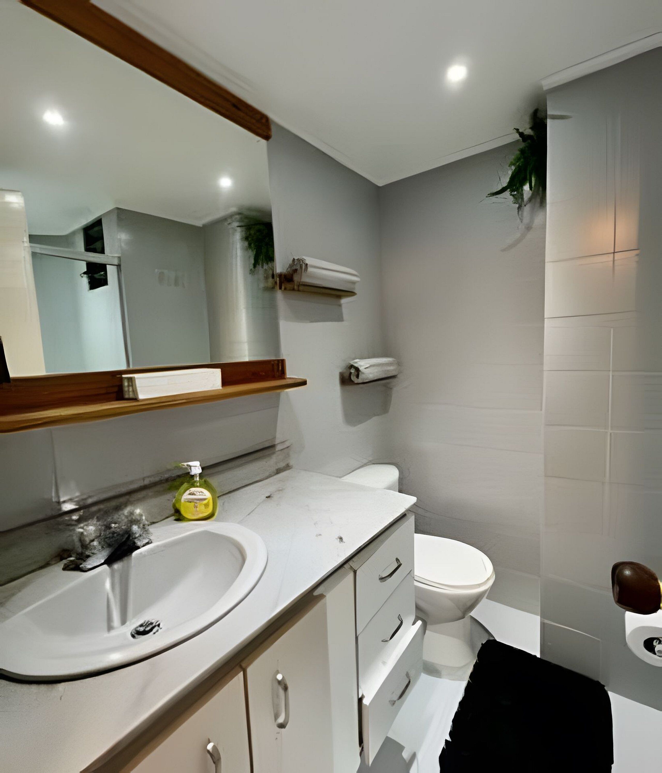A bathroom with a sink, mirror, toilet, and towel rack.