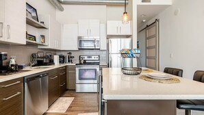 Una cocina moderna con armarios blancos, electrodomésticos de acero inoxidable y una isla central con asientos.