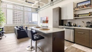 Una cocina moderna con una isla central, taburetes de bar y un área de comedor con sofá.