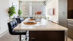Una cocina moderna con una isla central, zona de estar y ventanas amplias.