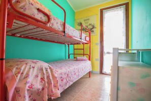 A bunk bed room with a door leading to a balcony, a poster on the wall, and a tiled floor. - Comfortable House with Large Terrace Sea View - Pistis - Green Coast-Arbus (Sardegna)