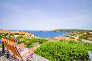 Une vue sur la côte, avec une chaise, de la verdure et des bâtiments.