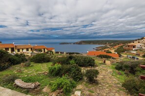 A coastal residential area with stone pathways, greenery, and houses with red roofs. - Comfortable House with Large Terrace Sea View - Pistis - Green Coast-Arbus (Sardegna)