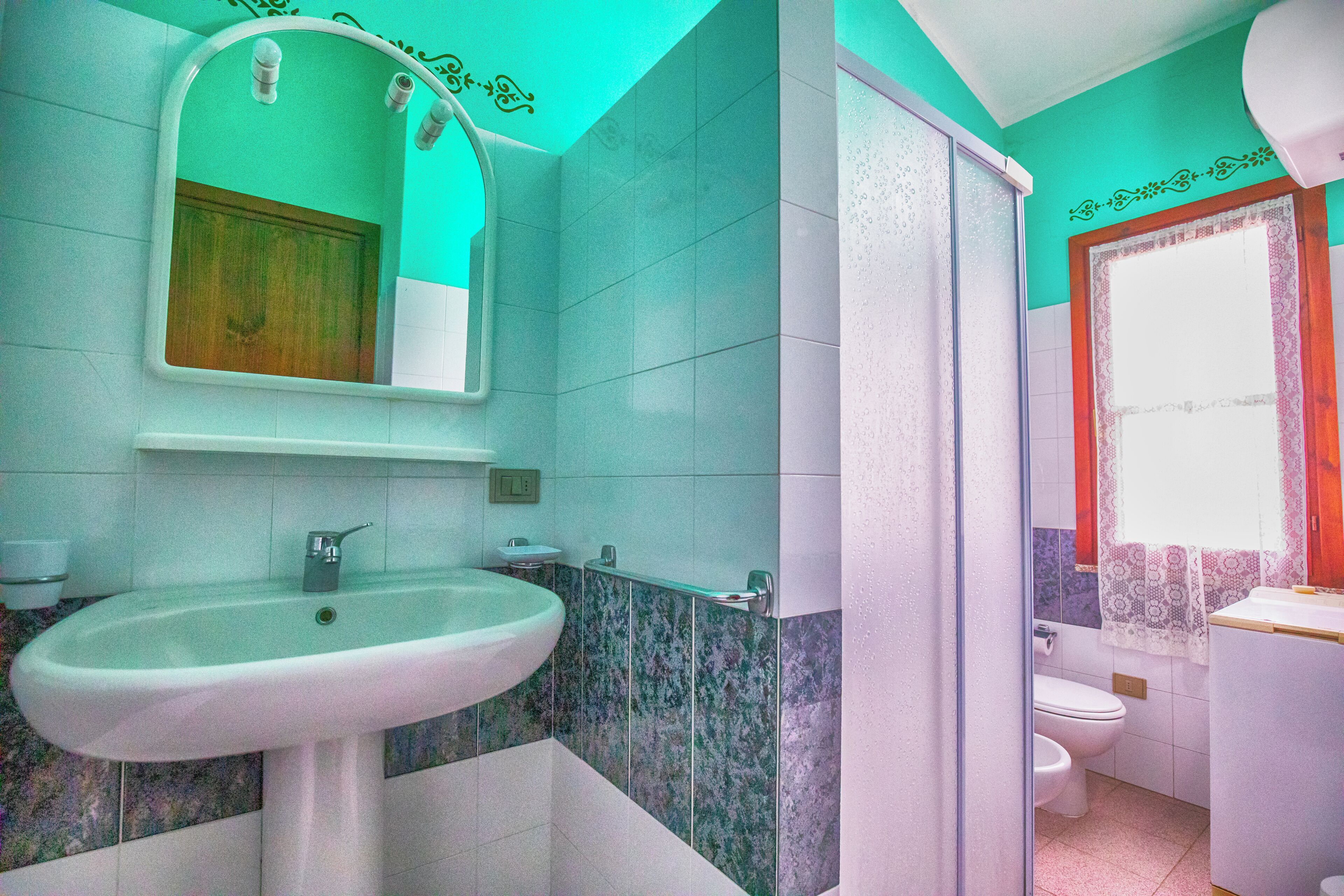 Un baño con lavamanos, espejo, inodoro y ducha.