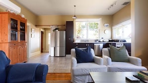A modern kitchen with a refrigerator, stove, and sink. There are two white sofas with blue cushions and a blue armchair. - Late-Georgian Escape near Launceston (Evandale)