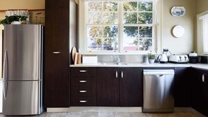 A modern kitchen with a stainless steel refrigerator, dark cabinetry, a dishwasher, and a window with a view of trees. - Late-Georgian Escape near Launceston (Evandale)