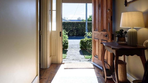 A wooden door leading to a stone pathway, a small table with a lamp, and a wicker basket. - Late-Georgian Escape near Launceston (Evandale)