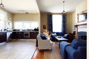 A modern kitchen with dark cabinetry, a dining area with a sofa and table, and a fireplace.