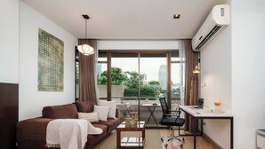 A modern apartment with a sofa, desk, chair, and a view of the city through large windows. - Quiet-NearTerminal21 Malls/BTSNana/SkylineView/Gym (Khlong Toei)