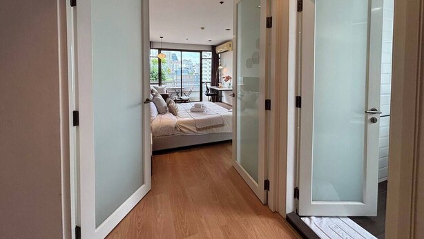 A narrow hallway leading to a bedroom with a bed, a desk, and a chair. - Quiet-NearTerminal21 Malls/BTSNana/SkylineView/Gym (Khlong Toei)