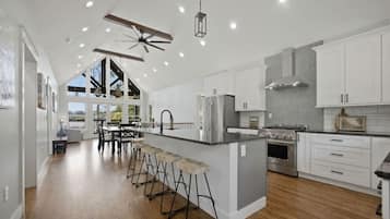 A spacious kitchen with a central island, bar stools, and a dining area with a view.