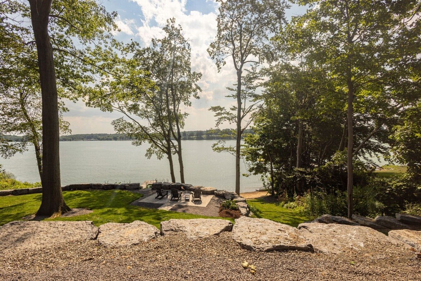 A lakeside outdoor seating area with stone benches and a fire pit.